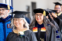 Dr. Diana Garza and Dr. Tod Treat are dressed in graduation attire and lead the graduation processional.