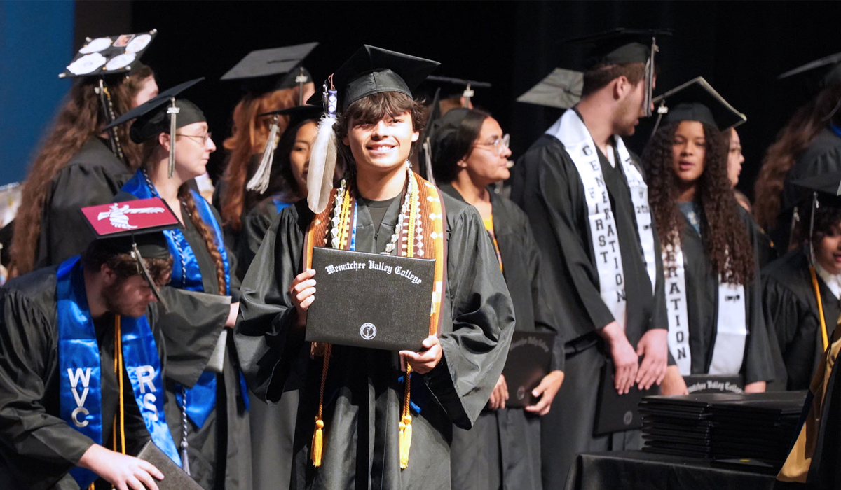 WVC Omak graduate on stage receiving diploma.