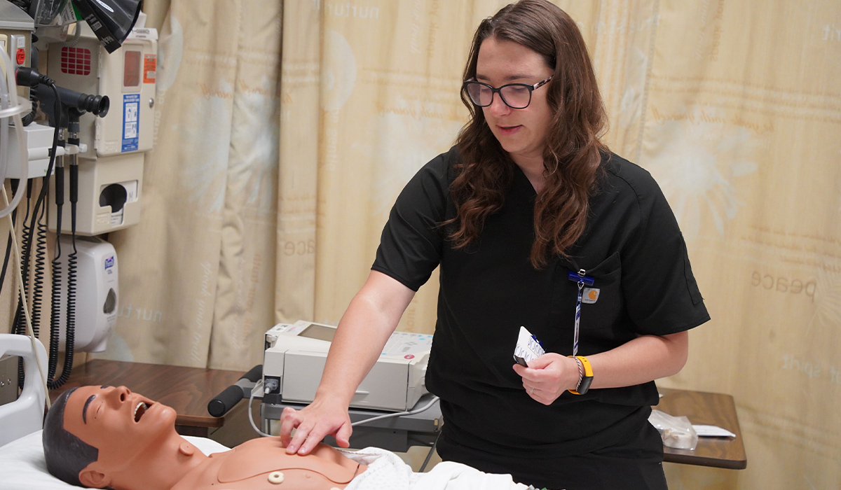 A medical assistant practices placing heart monitoring devices on a manikin.
