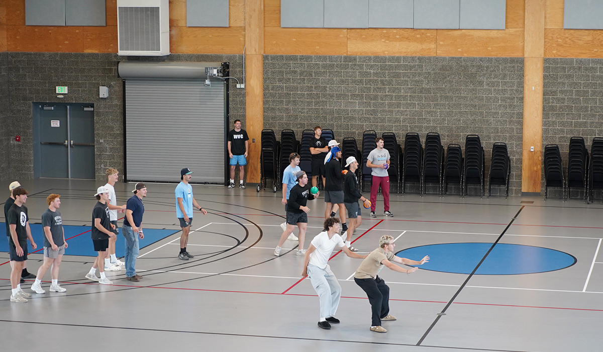 A group of athletes are in the Student Recreation Center basketball court playing dodgeball.