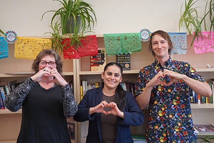 Dr. Maria Morales-Sanchez stands next to Saxon Spillman and Barbara Oldham, and they all make heart shapes with their hands.