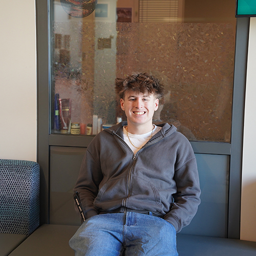 WVC student Ethan Kamphaus sits on a bench in front of an office window.