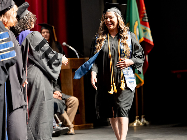 A WVC Omak graduate walks across the stage to meet the WVC Board of Trustees and receive her diploma.