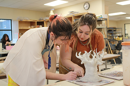 Professor Sarah Sprouse helps a student with her ceramics project.