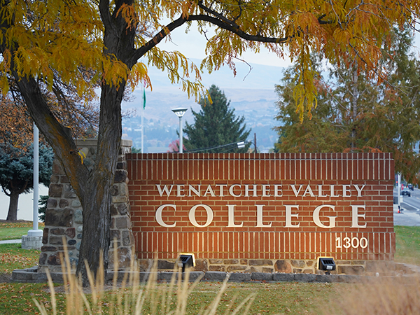 The brick Wenatchee Valley College entryway sign beneath a tree in autumn colors.